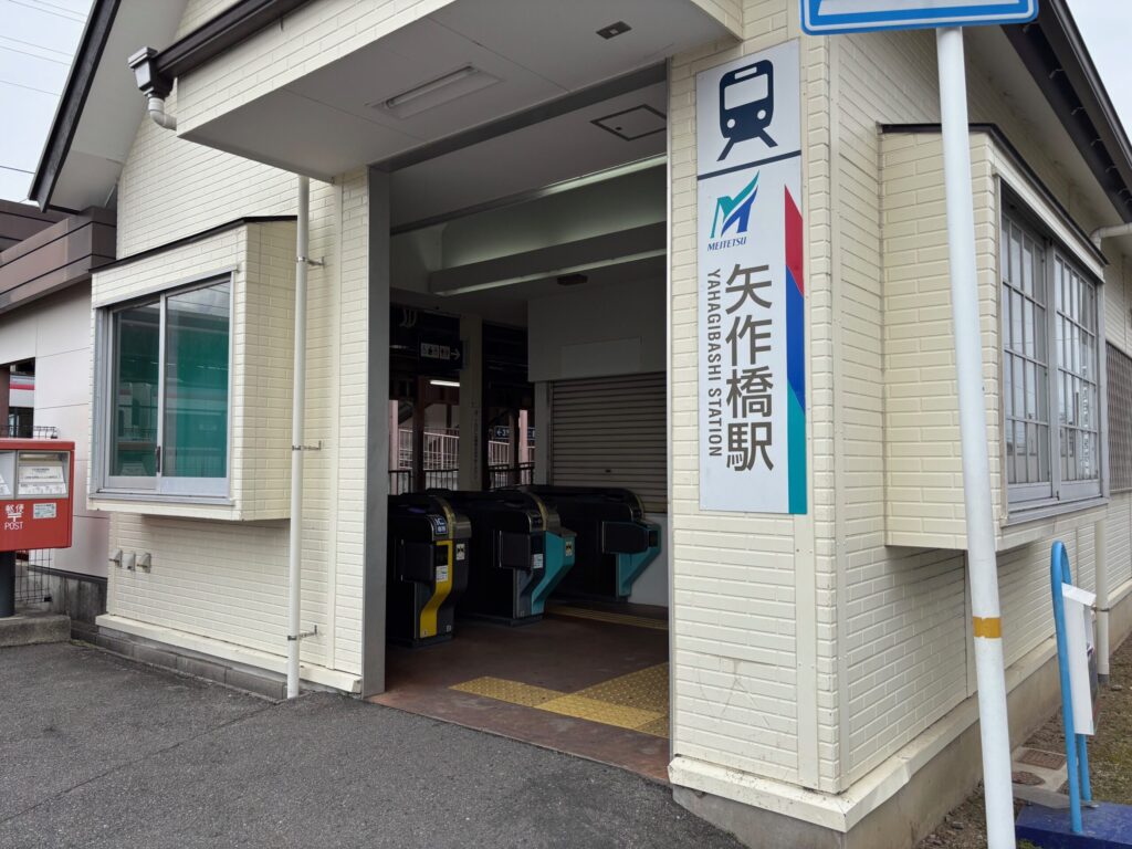 名鉄矢作橋駅（YAHAGIBASHI STATION）北口｜クリーム色のレンガ調壁・MEITETSUロゴ・赤いポスト 岡崎矢作南はなえみ墓園へ車で6分