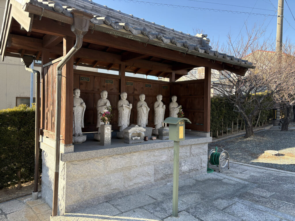 紫雲寺境内の六地蔵菩薩堂｜瓦屋根の覆屋の下、合掌する6体の石造地蔵菩薩像・献花・香炉・浄財箱（豊橋市高師本郷町）