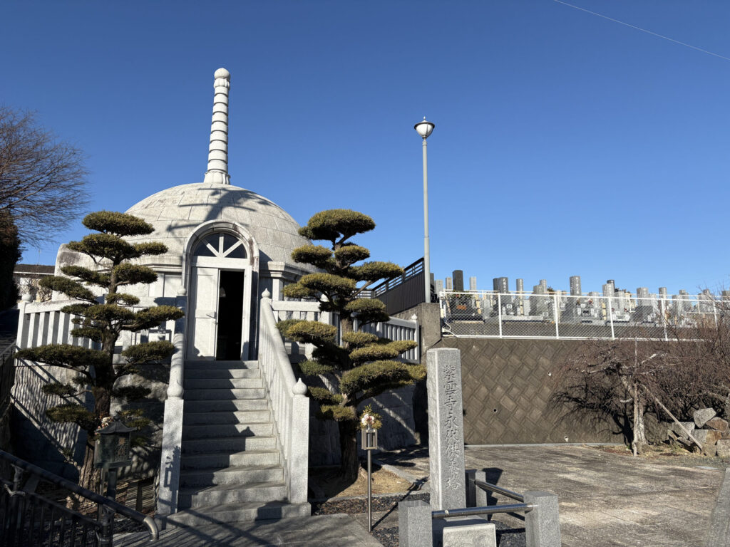 「紫雲寺永代供養塔」石碑のあるドーム型（覆鉢型）の石造永代供養塔｜松の植栽・既存墓地と一体化（平成19年建立）