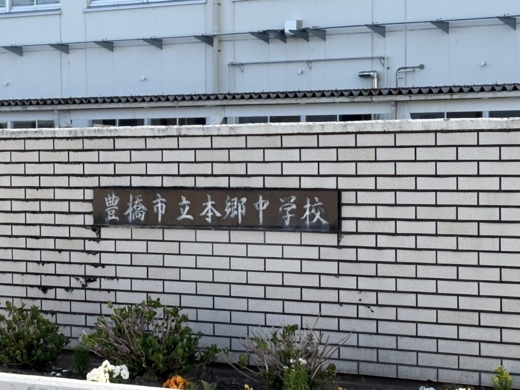 豊橋市立本郷中学校 銘板｜白いブロック塀に「豊橋市立本郷中学校」と刻まれた金属プレート・花壇（豊橋高師はなえみ墓園から徒歩6分）