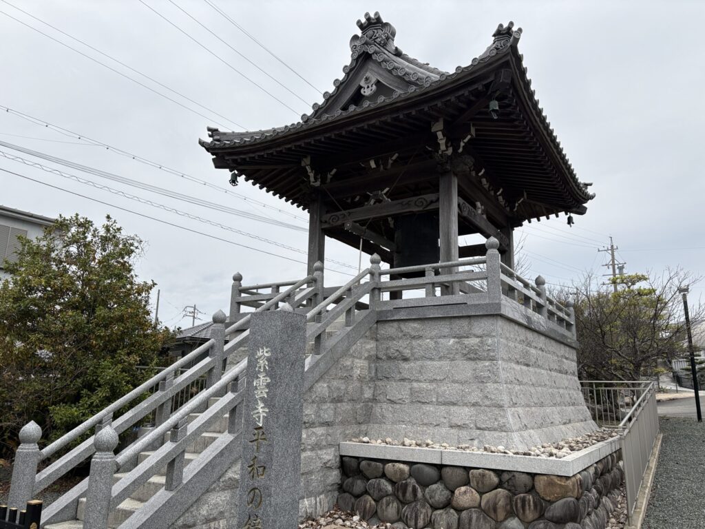 「紫雲寺平和の鐘」石碑のある鐘楼｜入母屋造の優美な屋根・梵鐘・石組みの基壇・御影石手すり（豊橋市高師本郷町）