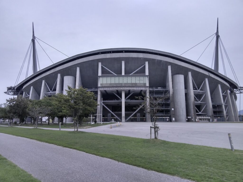 豊田スタジアム（TOYOTA STADIUM）正面外観｜斜張橋型の2本の白い支柱とコンクリートの重厚な外観 豊田はなえみ墓園から車で約10分