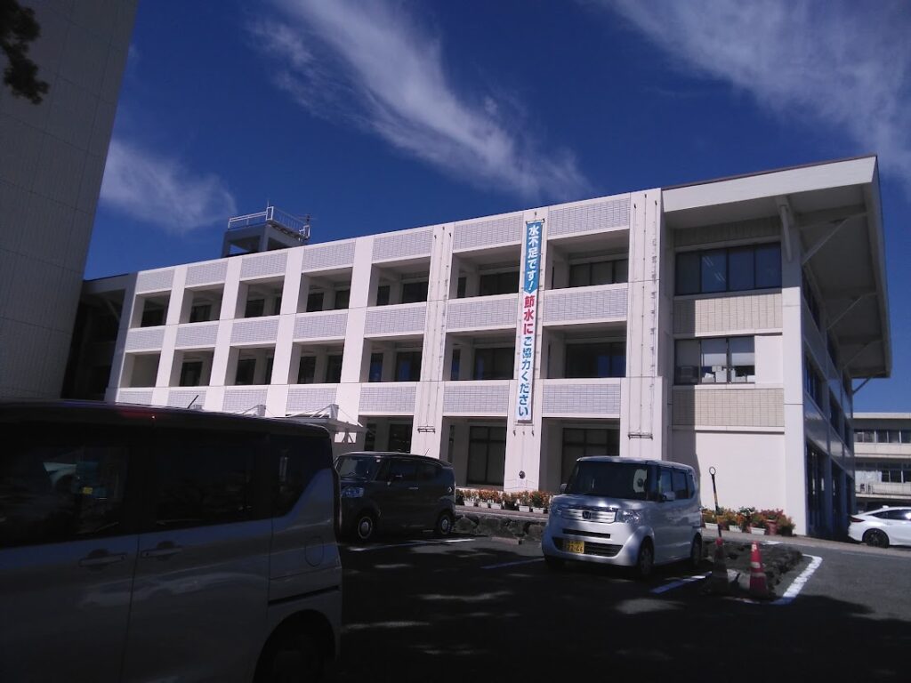 蒲郡市役所 外観｜白いタイル貼りの庁舎と「節水にご協力ください」の縦断幕 蒲郡はなえみ樹木葬への改葬許可申請窓口 蒲郡市役所から車で約17分
