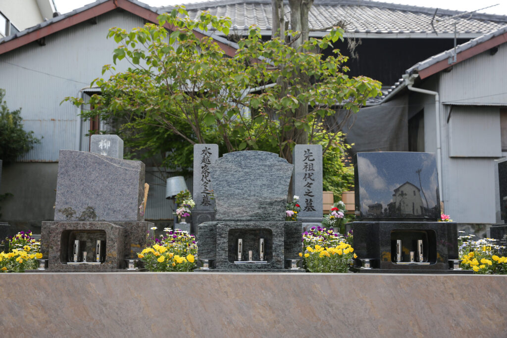 豊橋下地はなえみ墓園 洋型墓石3形式 並列展示 茶色マホガニーレッド御影石 青影スウェーデン斑御影石 黒影御影石 石製納骨室 ステンレス花立 赤レンガ基壇 大樹背景