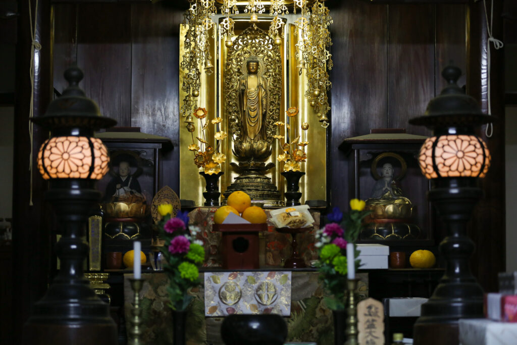専修院 阿弥陀如来立像 正面 金色須弥壇 黒灯籠 黄色いろうそく 黄色いみかん 紫・緑・ピンクの生花 桐紋葵紋 紫の前掛け 茶色木造内陣