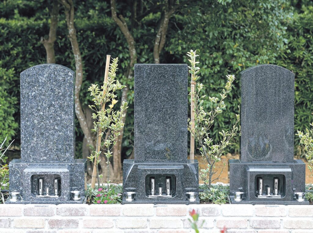 レンガ基壇に並ぶはなえみ墓園の和型墓石3基（新緑背景）