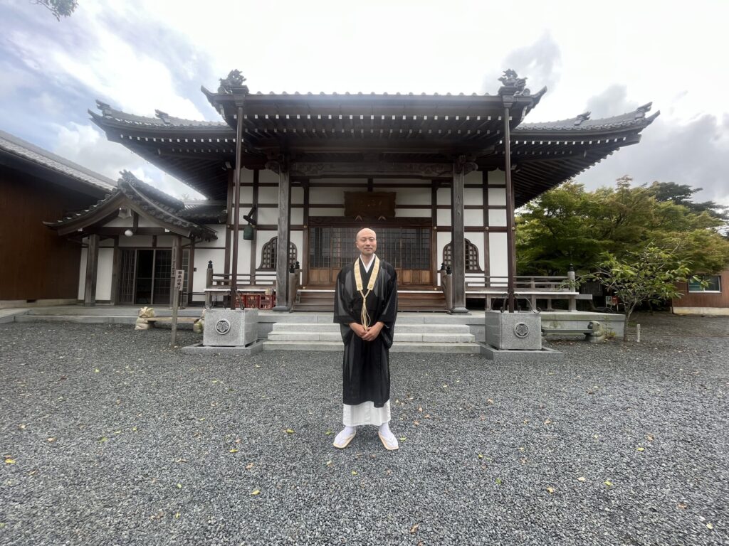 欣浄寺本堂前に立つ住職 祖父江義典さん（黒衣・白足袋）