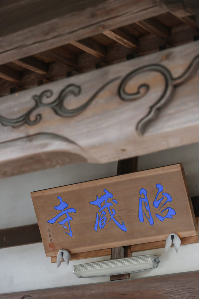 胎蔵寺の山号額（縦構図）｜青字で「胎蔵寺」と書かれた本堂軒下の木製扁額・沙扇書