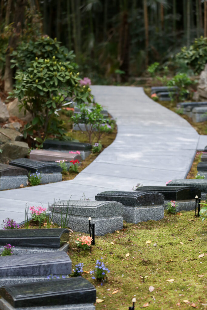 竹林を背景にカーブする石畳と板型墓石（阿久比はなえみ墓園の樹木葬・縦）