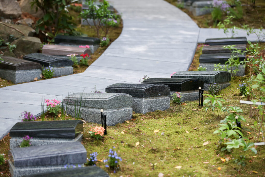 緩やかにカーブする石畳の園路と板型墓石の庭園（阿久比はなえみ墓園）