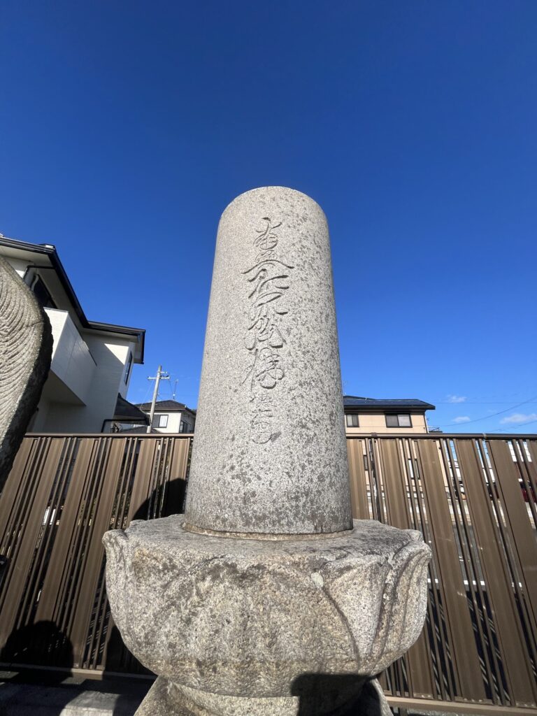 豊橋下地はなえみ墓園 南無阿弥陀佛 供養塔 圓柱形 蓮華座基壇 灰色御影石 抜けるような青空 茶色木製ボーダーフェンス 周辺住宅街