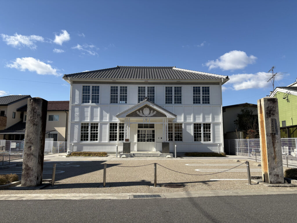 白い洋風2階建ての旧本宿村役場と石標