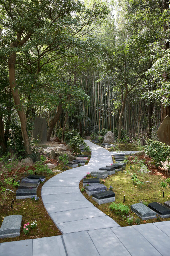 竹林を背景にした樹木葬の石畳の小径と板型墓石（阿久比はなえみ墓園）