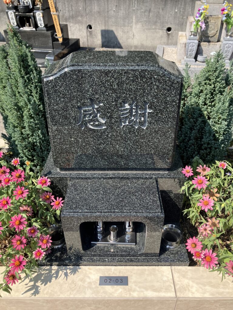 「感謝」と刻まれた洋型のお墓とピンクの花｜美浜はなえみ墓園の洋型墓石